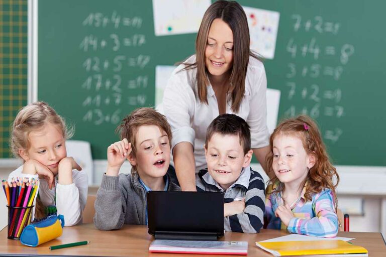 Lehrerin zeigt Schülern etwas am Laptop, Foto:  Adobe Stock